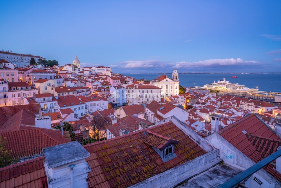 View of colourful buildings and red rooftops at dusk in the Alfama District, Lisbon, Portugal, Europe