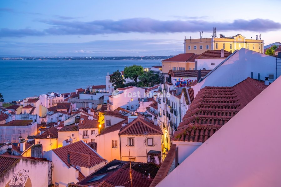 View of colourful buildings and red rooftops at dusk in the Alfama District, Lisbon, Portugal, Europe