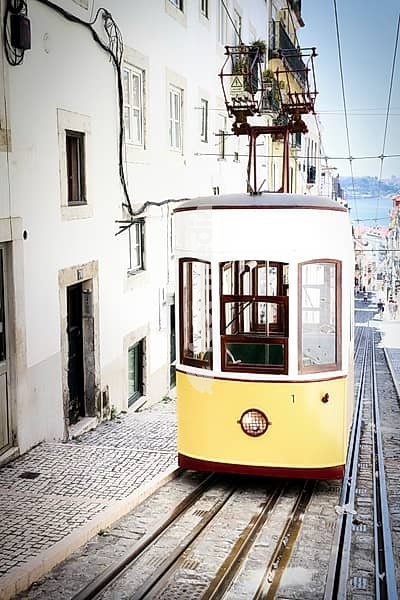 A funicular railway car of the historic Elevador da Bica in Lisbon stands empty at the top station