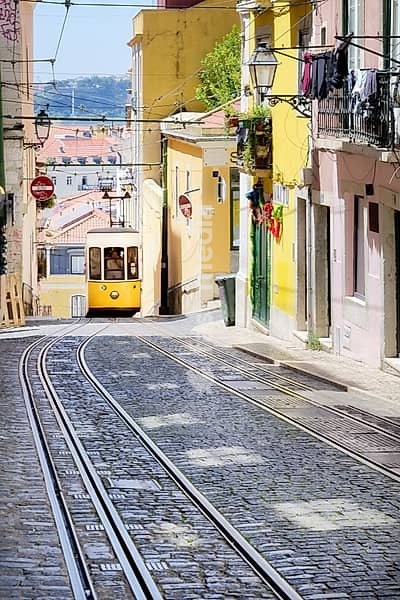 A car of the Elevador da Bica funicular in Lisbon comes up the hill in the narrow old town streets of lisbon