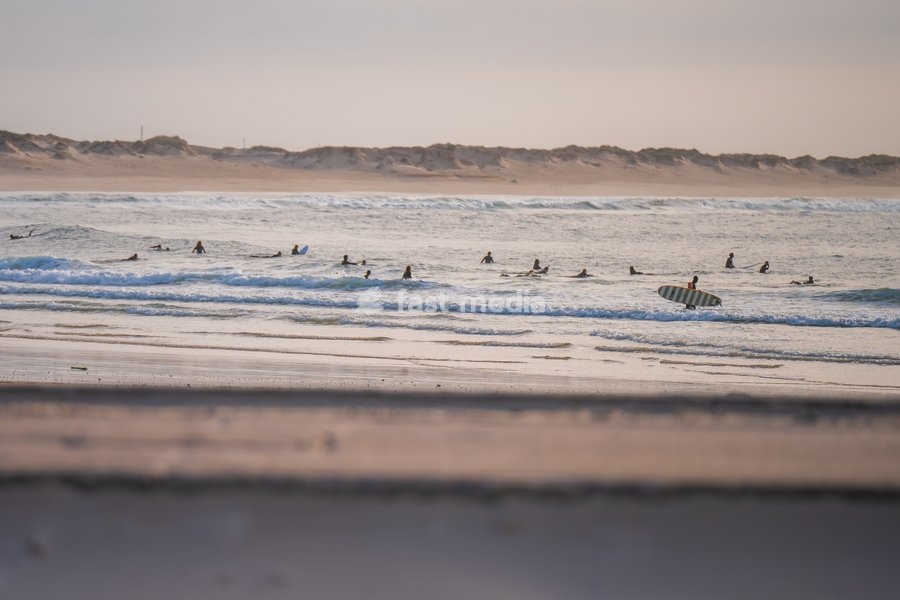 Silhouette of surfers in the water waiting for the right wave in Baleal Island beach