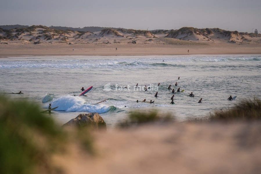 Silhouette of surfers in the water waiting for the right wave in Baleal Island beach