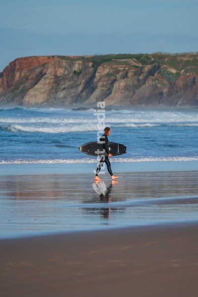 Surfer walking out of the water in Baleal Island beach, Portugal