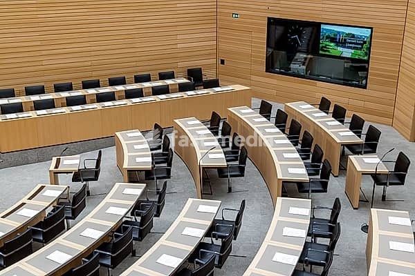Plenary hall deserted with the seats of deputies and the government bank. Behind it is the coat of arms of the federal state. The state parliament of Baden-Württemberg is the state parliament based in Stuttgart, Baden-Württemberg, Germany