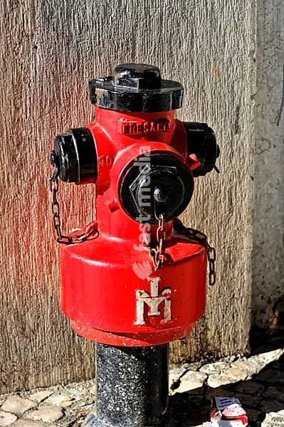 An eye-catching red hydrant on a stone wall in an urban setting, Lisbon, Portugal