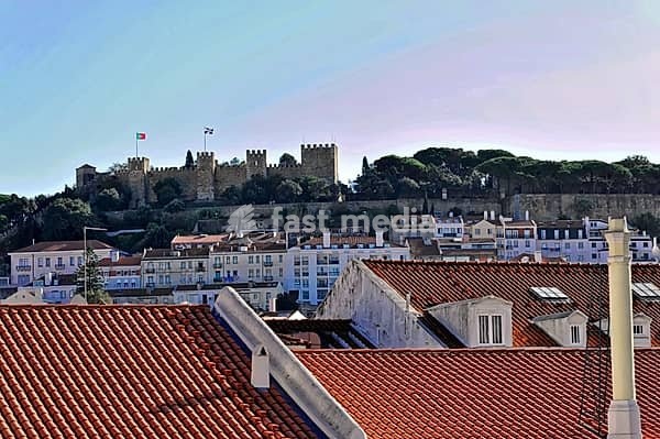 View over rooftops of a castle on a wooded hill, Lisbon, Portugal
