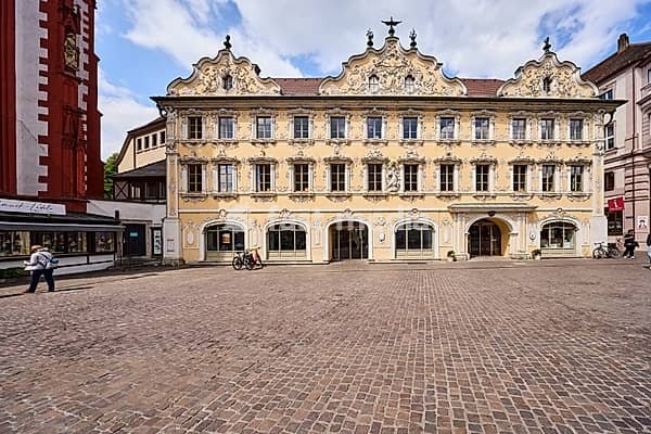 Public library Max-Heim-Bücherei, tourist information, falcon house, historic building, rococo style, façade with windows, stucco decoration and door, gable, cobblestone square, pedestrian as a secondary motif, blue sky, cumulus clouds, market square, Würzburg, Lower Franconia, district-free city,…