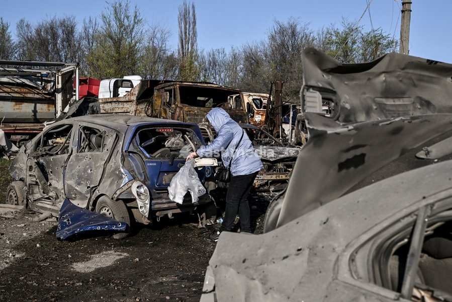 A woman stands by a car destroyed by a Russian drone strike at a parking lot in Zaporizhzhia, Ukraine, April 15, 2026. The attack killed a 74-year-old woman and damaged the stop, a parking lot, and nearby residential buildings