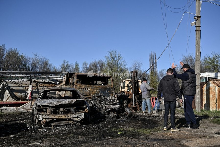 People stay at a parking lot affected by a Russian drone strike in Zaporizhzhia, Ukraine, April 15, 2026. The attack killed a 74-year-old woman and damaged the stop, a parking lot, and nearby residential buildings