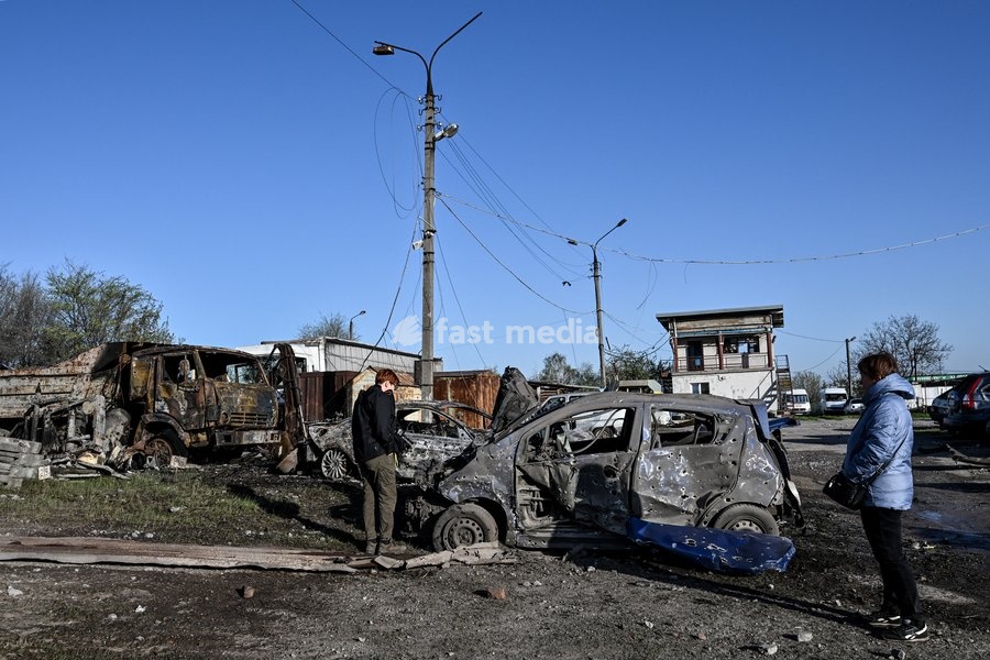 Women look at a car destroyed by a Russian drone strike at a parking lot in Zaporizhzhia, Ukraine, April 15, 2026. The attack killed a 74-year-old woman and damaged the stop, a parking lot, and nearby residential buildings