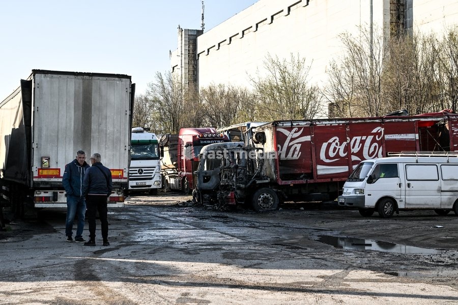 Two men stand by a truck damaged by a Russian drone strike at a parking lot in Zaporizhzhia, Ukraine, April 15, 2026. The attack killed a 74-year-old woman and damaged the stop, a parking lot, and nearby residential buildings