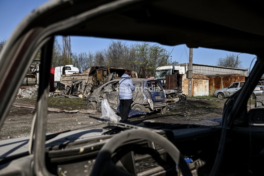 A woman stands by a car destroyed by a Russian drone strike at a parking lot in Zaporizhzhia, Ukraine, April 15, 2026. The attack killed a 74-year-old woman and damaged the stop, a parking lot, and nearby residential buildings