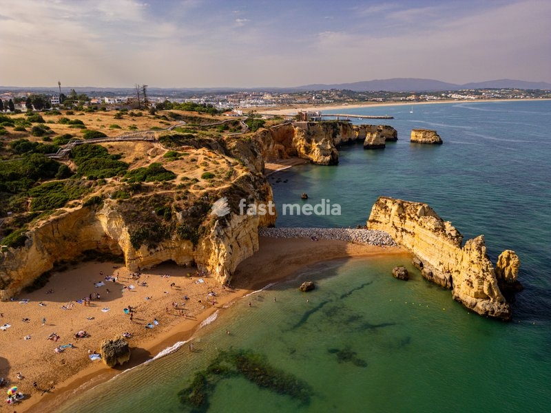 View of beach cliffs at sunset near Lagos in Algarve region of Portugal with people enjoying the sandy shore
