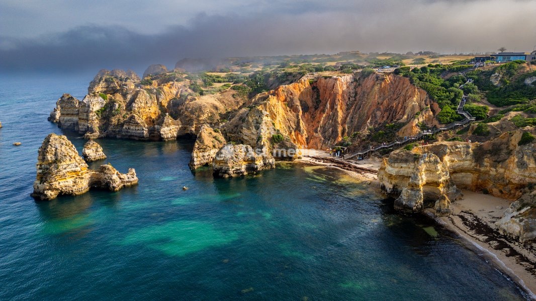 Beach cliffs surround the ocean with rocky formations at sunset in Algarve, Portugal near Lagos