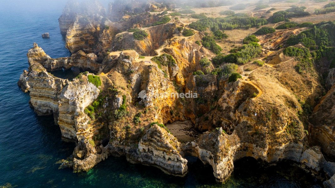 Sunset view of beach cliffs near Lagos in Algarve Portugal with ocean and land meeting at dusk
