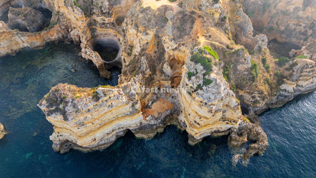 Sunset over beach cliffs showing waves and rocks along the coast in Algarve Portugal