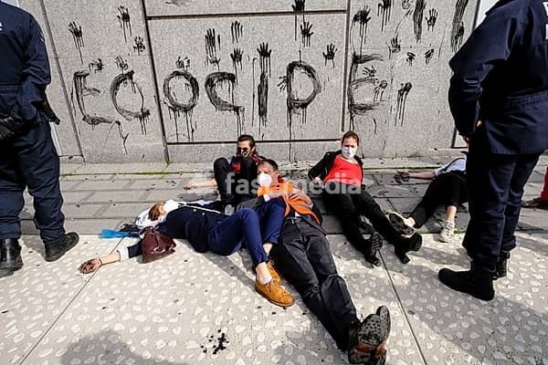 Belgium, Brussels, April 1, 2021: demonstration of the global environmental movement Extinction Rebellion in front of the headquarters of EuroClear, to protest against the role of the banking and finance sector in the climate crisis. Activists lying on the floor with hands and word ecocide drawn…