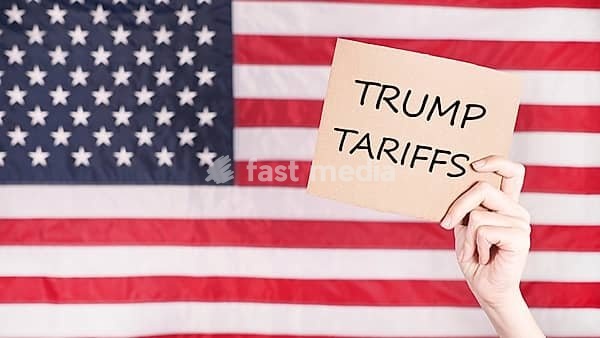 Hand holding sign with text Trump Tariffs against American flag on background