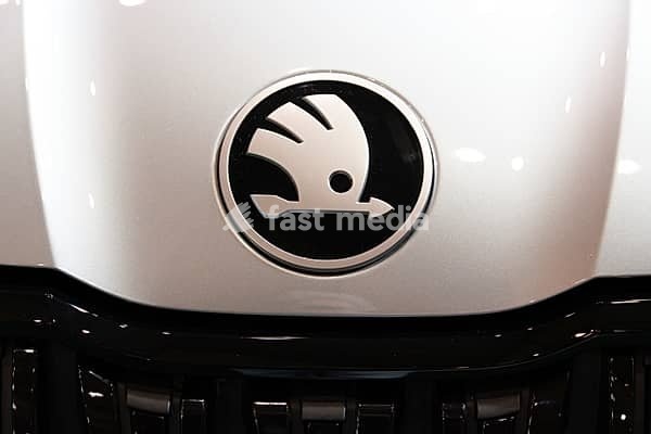 LISBON, PORTUGAL - MAY 16, 2026: Symmetrical front macro close-up of the round chrome and black Skoda winged arrow emblem on a silver metallic bonnet at the ECAR Show electric vehicle exhibition