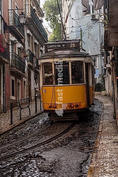 Historische Strassenbahn an einem regnerischen Frühlingstag in der Altstadt von Lissabon, Portugal. Historical Tram of the famous line 28 on a rainy day in the narrow alleys of the old town of Lisbon, Portugal