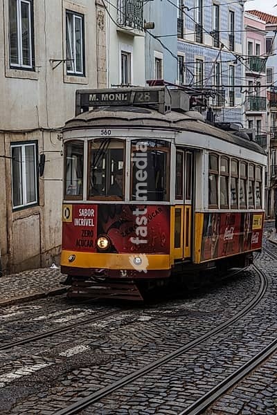 Historische Strassenbahn an einem regnerischen Frühlingstag in der Altstadt von Lissabon, Portugal. Historical Tram of the famous line 28 in the narrow alleys of the old town of Lisbon, Portugal