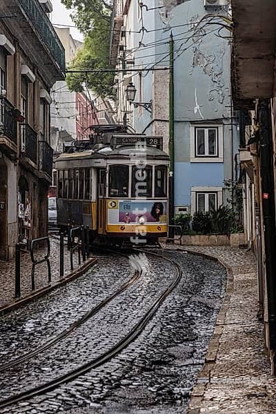 Historische Strassenbahn an einem regnerischen Frühlingstag in der Altstadt von Lissabon, Portugal. Historical Tram of the famous line 28 on a rainy day in the narrow alleys of the old town of Lisbon, Portugal