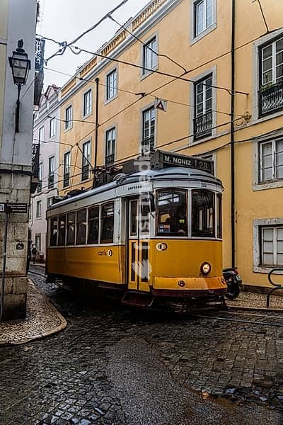 Historische Strassenbahn an einem regnerischen Frühlingstag in der Altstadt von Lissabon, Portugal. Historical Tram of the famous line 28 on a rainy day in the narrow alleys of the old town of Lisbon, Portugal