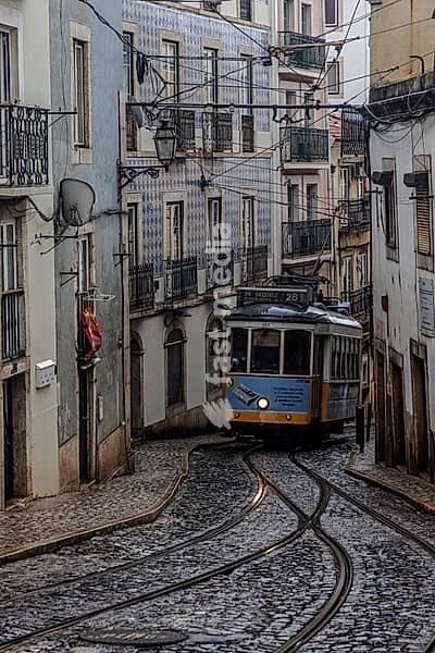 Historische Strassenbahn an einem regnerischen Frühlingstag in der Altstadt von Lissabon, Portugal. Historical Tram of the famous line 28 on a rainy day in the narrow alleys of the old town of Lisbon, Portugal