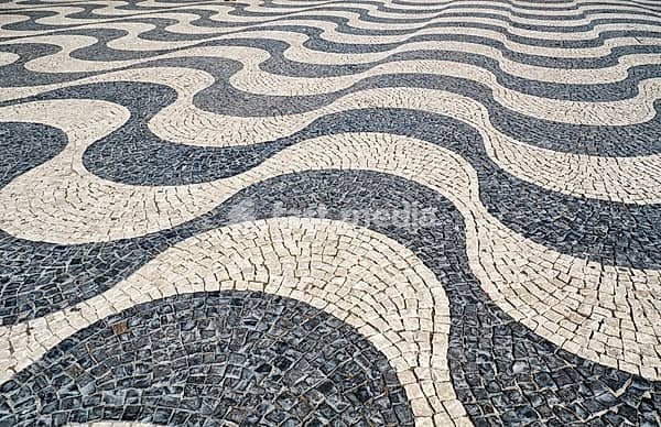 The wave shape pattern of tradition Portuguese pavement mosaic designed with black and white stones of basalt and limestone on the Rossio square. Lisbon. Portugal