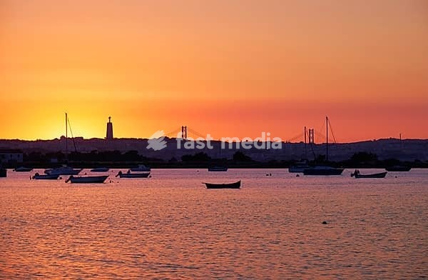 Sunset view of the river Tejo, 25th of April Bridge and statue of Christ the King in Lisbon, Portugal