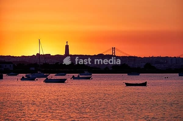 Sunset view of the river Tejo, 25th of April Bridge and statue of Christ the King in Lisbon, Portugal