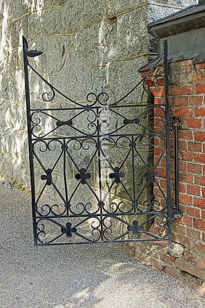 Old wrought iron cemetery gate mounted on red brick wall, Vanaja, Finland