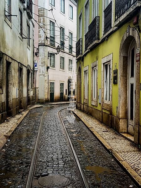 Narrow street with tram tracks in the old town of Lisbon, Portugal. Colourful facades in a narrow alley in the old town of Lisbon, Portugal