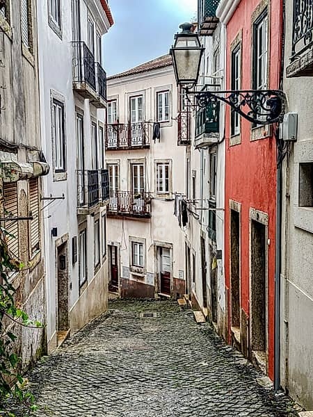 Colourful facades on a narrow alley in the old town of Lisbon, Portugal. Colourful facades and wrought-iron lanterns in a narrow alley in the old town of Lisbon, Portugal