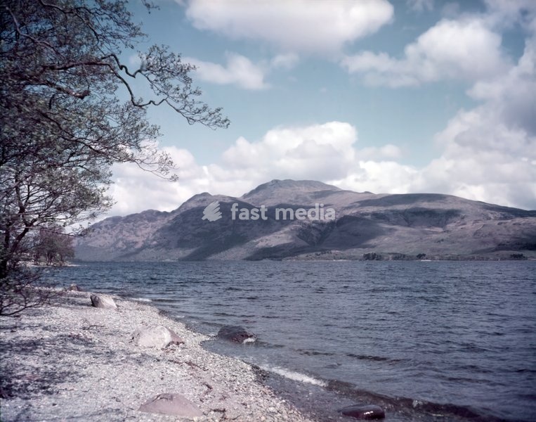 Loch Lomond and Ben Lomond, Scotland, c1955. Popular leisure destination featured in the song "The Bonnie Banks o' Loch Lomond". The loch is surrounded by hills including Ben Lomond on the eastern shore, which is 973.7 metres (3,195 feet) in height, and the most southerly of the Scottish Munro peaks
