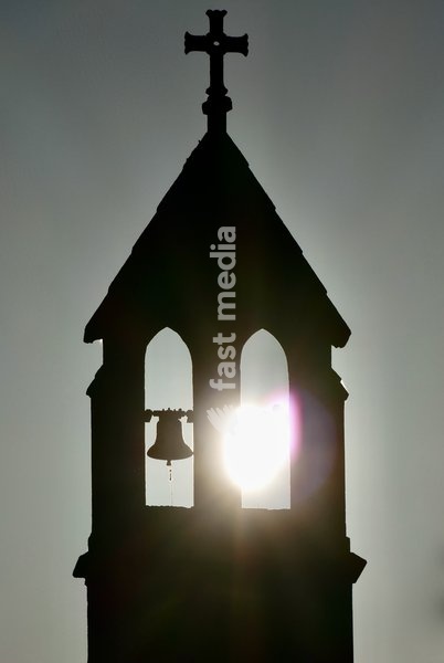 The rising sun appears through the bell tower of the ancient church