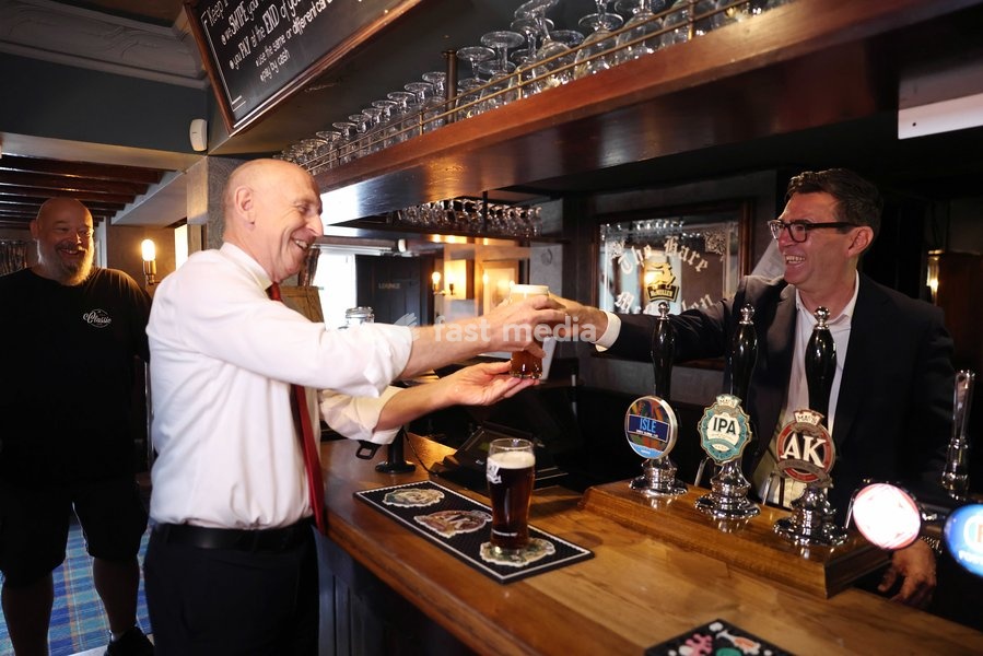 23/07/2026. Harlow, United Kingdom. Prime Minister Andy Burnham pours a pint for John Healey, Chancellor of the Exchequer as they visit the Hare pub as the government announces a 20 percent cut in business rates for pubs, clubs and live music venues