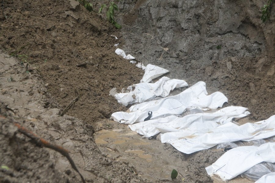 Rescue workers and officials manage a mass burial trench for unidentified remains recovered after severe flash floods in Gokarna, Kathmandu, Nepal, Tuesday, Sept. 1, 2026. Authorities initiated temporary burials as morgue capacities reached limits following the disaster