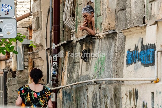 woman on a balcony observing a dilapidated street, Tbilisi, Georgia, Asia
