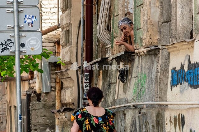woman on a balcony observing a dilapidated street, Tbilisi, Georgia, Asia