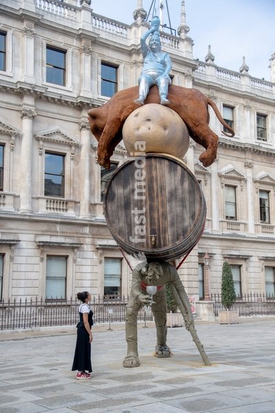 Visitors interact with 'Stack' by Nicole Eisenman, 2022-2024. Made with bronze, oak wood, mineral material, aluminium, and steel and standing at 820 x 335 x 346 cm