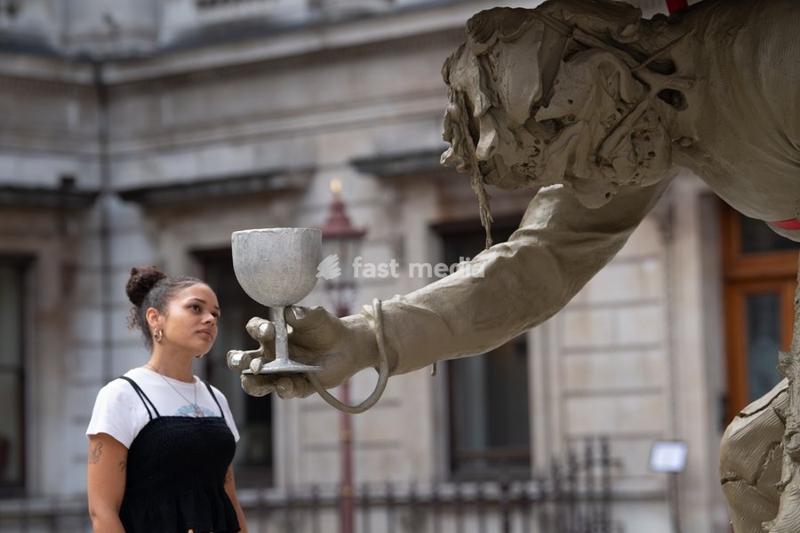 Visitors interact with 'Stack' by Nicole Eisenman, 2022-2024. Made with bronze, oak wood, mineral material, aluminium, and steel and standing at 820 x 335 x 346 cm