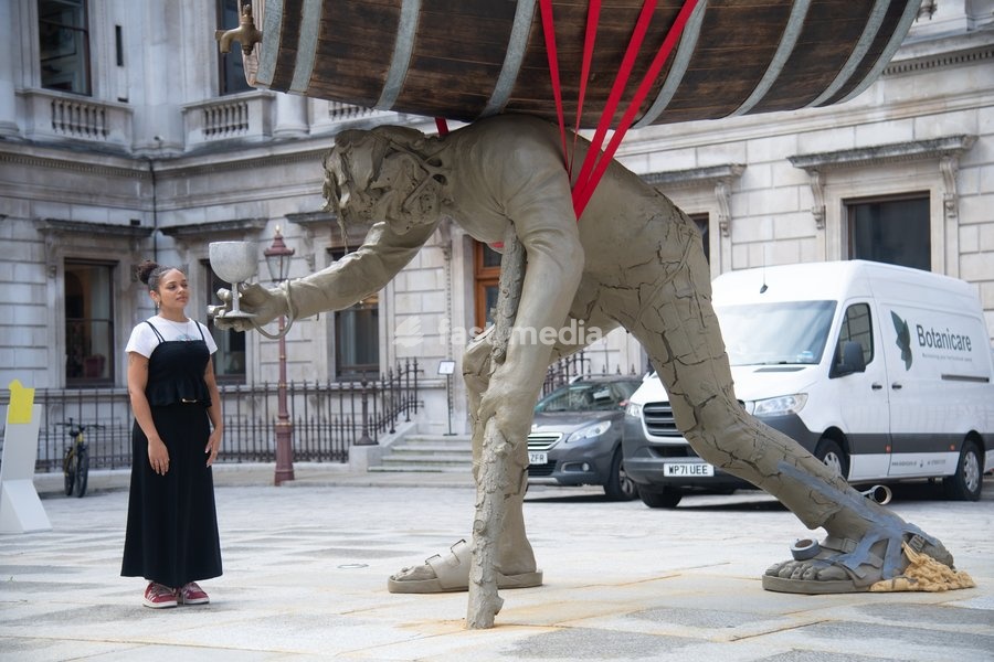 Visitors interact with 'Stack' by Nicole Eisenman, 2022-2024. Made with bronze, oak wood, mineral material, aluminium, and steel and standing at 820 x 335 x 346 cm