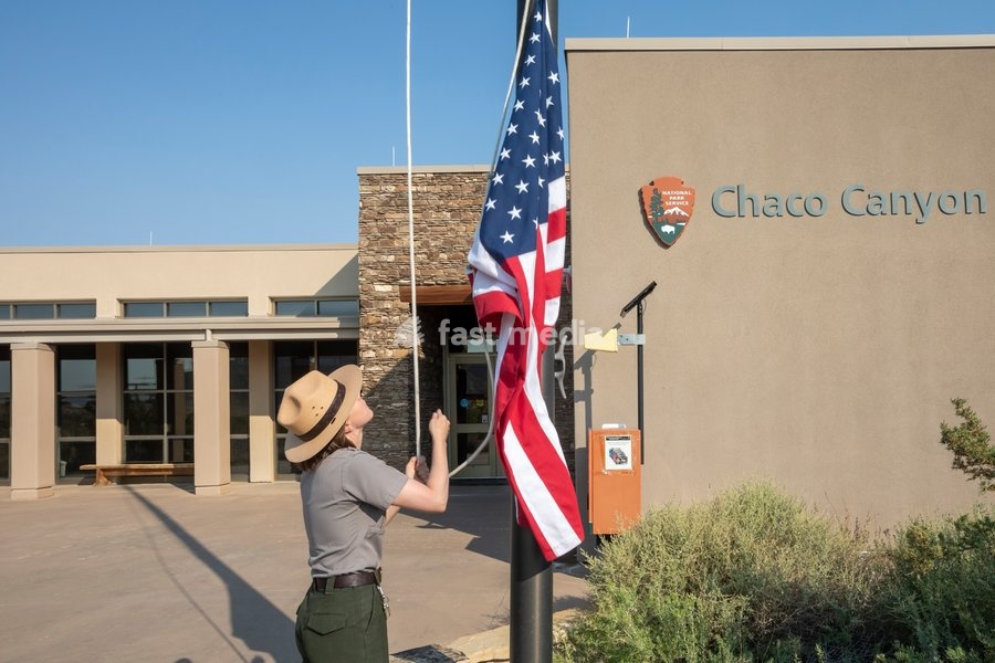 A park ranger raises the American flag at the Chaco Culture National Historical Park in New Mexico. The park preserves the remnants of the Chacoan culture that thrived here from the mid 800s to the late 1100s. Many supporters of the Park are opposing the Trump Administration's plan to remove a…