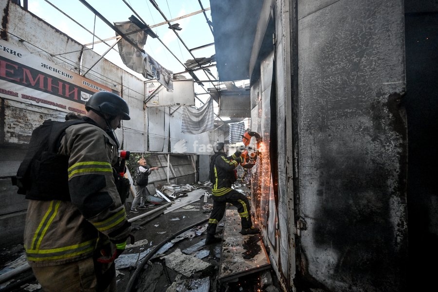 A State Emergency Service rescuer uses a cut-off saw to try to open the deformed metal door of a shipping container while extinguishing a fire at the Central Clothes Market (Anholenko) in Zaporizhzhia, Ukraine, September 26, 2026. The market sustained significant damage in a Russian drone attack
