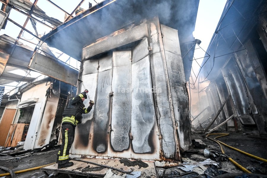 A State Emergency Service rescuer tries to open the deformed metal door of a shipping container while extinguishing a fire at the Central Clothes Market (Anholenko) in Zaporizhzhia, Ukraine, September 26, 2026. The market sustained significant damage in a Russian drone attack
