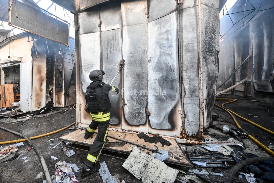 A State Emergency Service rescuer tries to open the deformed metal door of a shipping container while extinguishing a fire at the Central Clothes Market (Anholenko) in Zaporizhzhia, Ukraine, September 26, 2026. The market sustained significant damage in a Russian drone attack