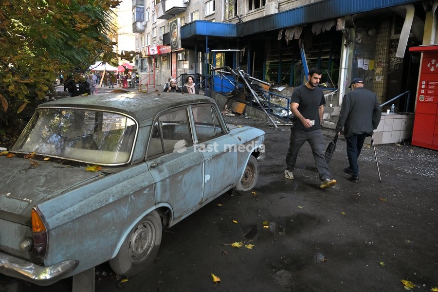People walk past a car and a supermarket in the Solomianskyi district, damaged by a Russian drone attack, Kyiv, Ukraine, September 26, 2026. During the morning assault on the capital, a Russian drone exploded close to the residential building. A fire covering 400 square metres broke out, destroying…