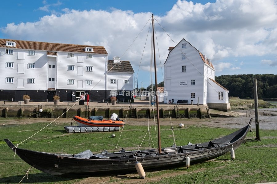 The Tide Mill, Woodbridge, one of only a handful in the world still producing flour on a regular basis and among the first tide mills in the country, working on the same site for over 850 years. A viking replica boat is in the foreground. Woodbridge on the River Deben near Ipswich, Suffolk. United…