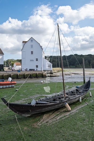 The Tide Mill, Woodbridge, one of only a handful in the world still producing flour on a regular basis and among the first tide mills in the country, working on the same site for over 850 years. A viking replica boat is in the foreground. Woodbridge on the River Deben near Ipswich, Suffolk. United…